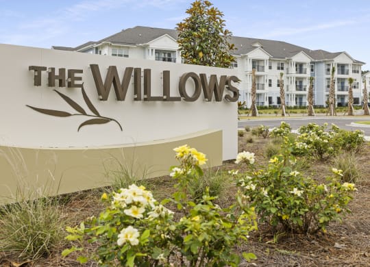 a sign for the willows with flowers in front of a building