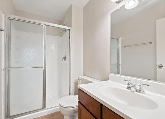 A white bathroom with a toilet, sink, and shower.