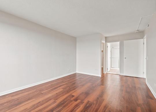 A bedroom with wooden floors and white walls.