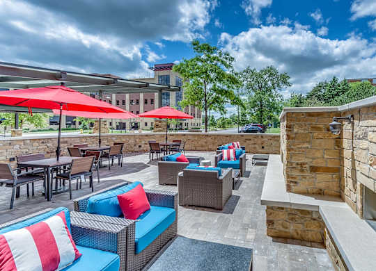 A patio with red umbrellas and blue couches.