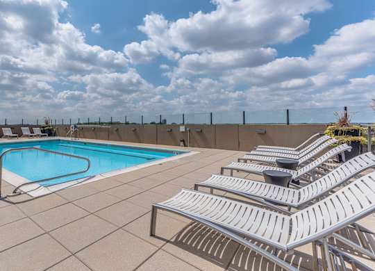 A pool with a metal railing and sun loungers.