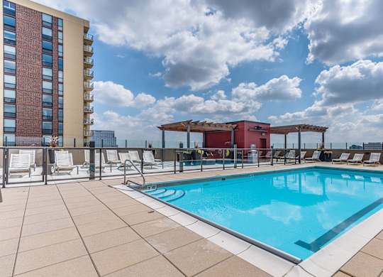 A large outdoor swimming pool with a red building in the background.