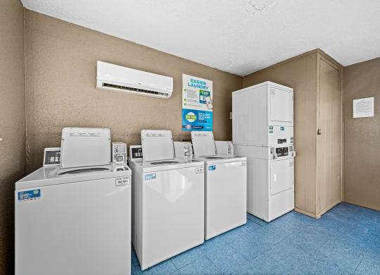 four sets of washing machines and refrigerators in a utility room with a row of
