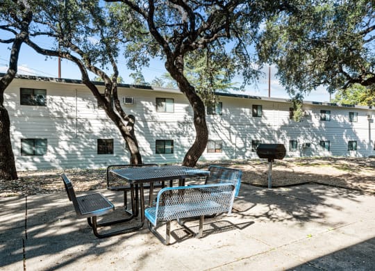 a patio with a table and chairs in front of a building