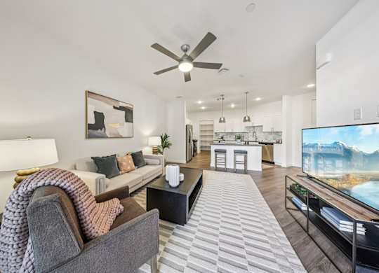 A modern living room with a grey sofa and a large television.at Fora Apartments, Las Vegas Nevada