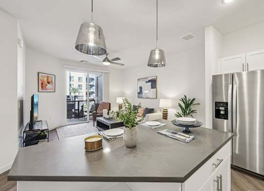 A modern kitchen with a stainless steel refrigerator and a dining table at Fora Apartments, Las Vegas, NV