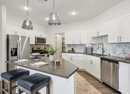 A kitchen with a bar area and stools.at Fora Apartments, Las Vegas