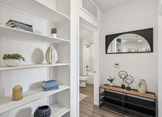 A bathroom with a mirror and a shelf with decorative items.at Fora Apartments, Las Vegas