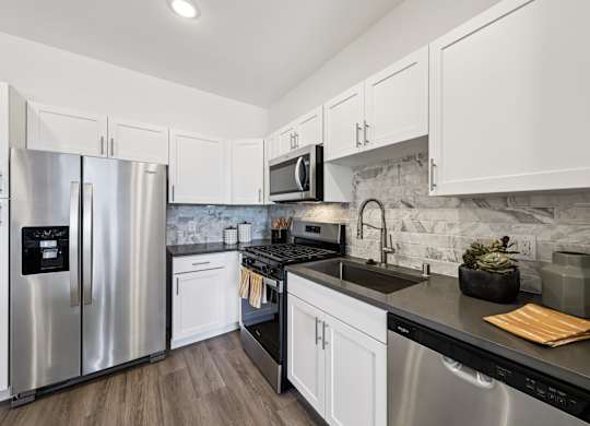 A modern kitchen with white cabinets and stainless steel appliances.at Fora Apartments, Las Vegas