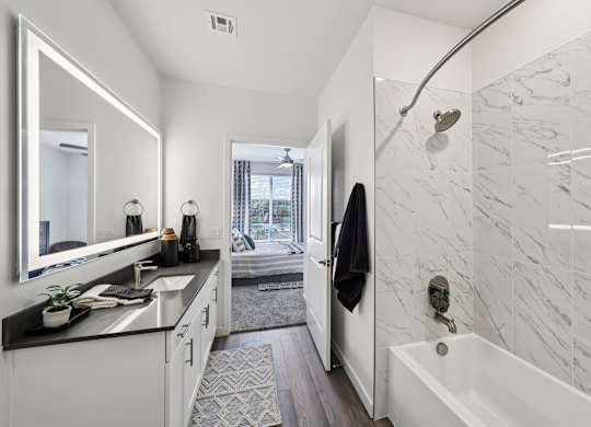 A bathroom with a marble wall and a white bathtub.at Fora Apartments, Nevada, 89183