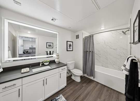A bathroom with a white sink and a large mirror.at Fora Apartments, Las Vegas, NV 89183
