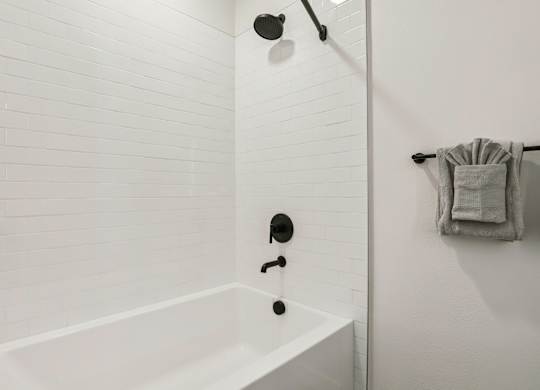 A white bathroom with a white tub and white tiles. at Lura Vegas Apartments, Las Vegas, NV