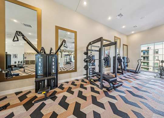 A gym with a variety of equipment including a squat rack, a leg press machine, and a treadmill.at Fora Apartments, Nevada