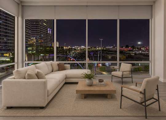 A modern living room with a large window overlooking the city at night.