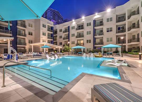 A large swimming pool surrounded by apartment buildings at night.