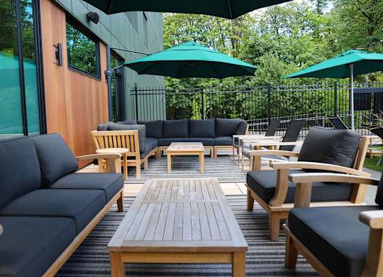 A patio with black couches and wooden tables.
