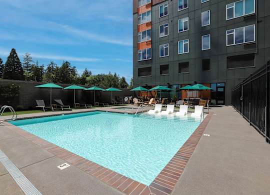 A large swimming pool with a red brick border and a black fence.