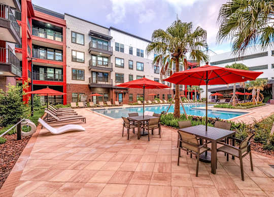 A pool surrounded by chairs and umbrellas in a courtyard.at Parkway Crossings, Kissimmee, FL