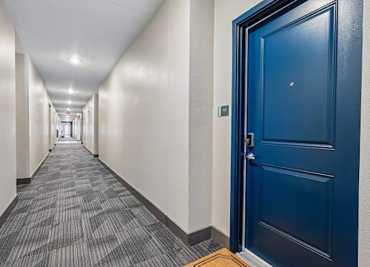 A long hallway with a blue door at the end.