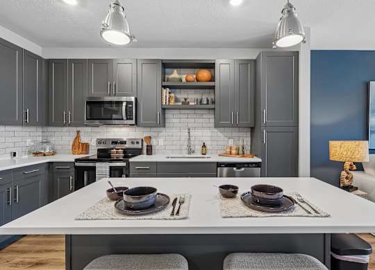 A modern kitchen with a dining table set for two.