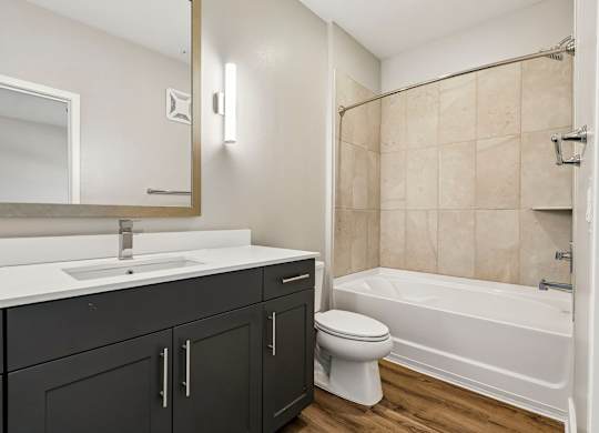 A bathroom with a white sink and black cupboards.