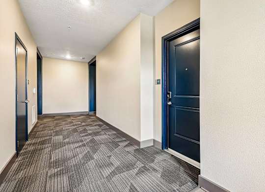 A hallway with a carpeted floor and a blue door.