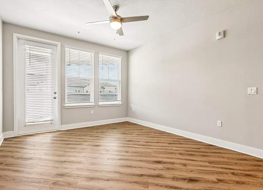 A room with a ceiling fan and wooden flooring.