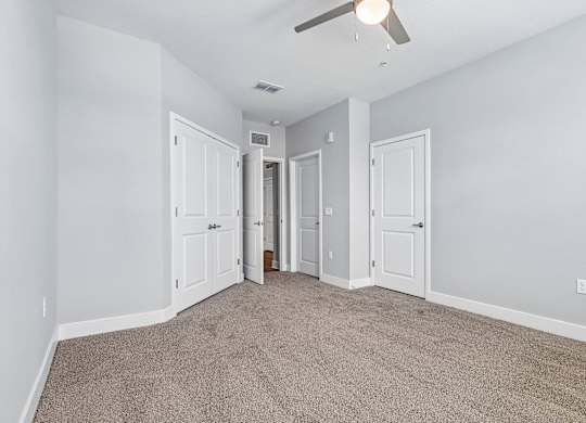 A room with a carpeted floor and a ceiling fan.