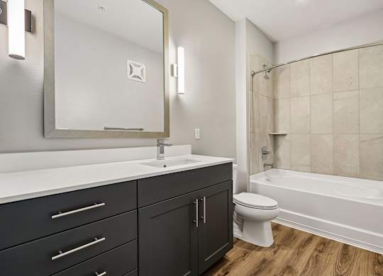A bathroom with a white sink, black drawers, and a white toilet.
