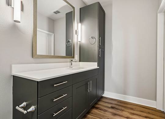 A bathroom with a sink, mirror, and cabinets.
