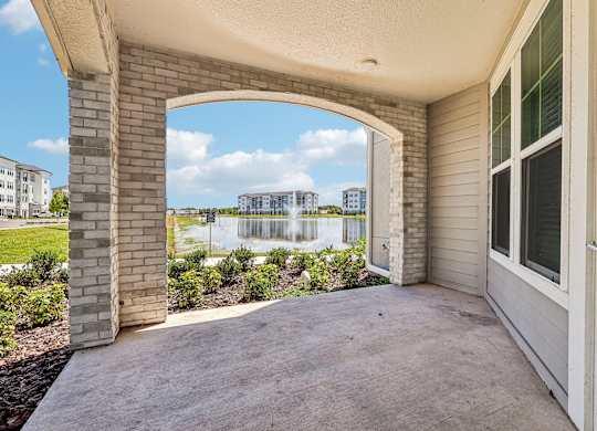 A patio with a white door and a view of a waterfall and buildings in the distance.