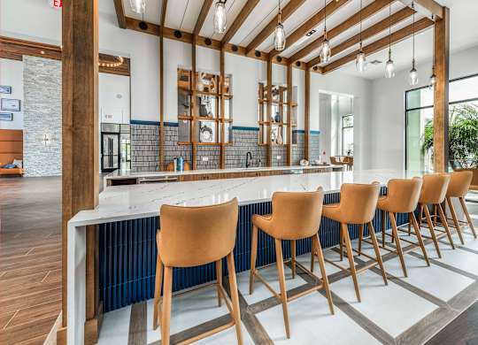 A kitchen with a long bar and chairs.