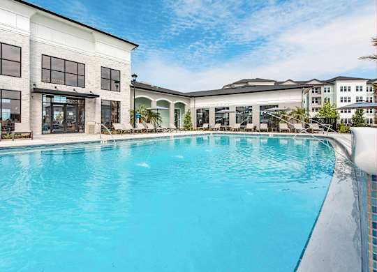 A large swimming pool in front of a building with a white facade.