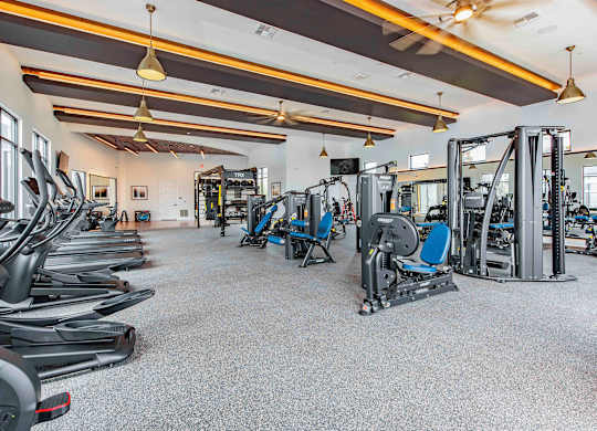 A gym with a variety of equipment including treadmills, weights, and exercise machines.