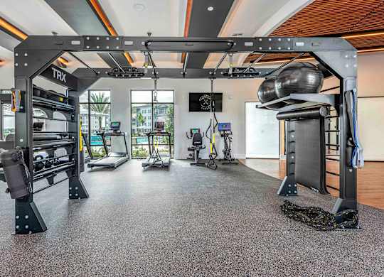 A gym with a variety of equipment including a treadmill, a stationary bike, and a rowing machine.
