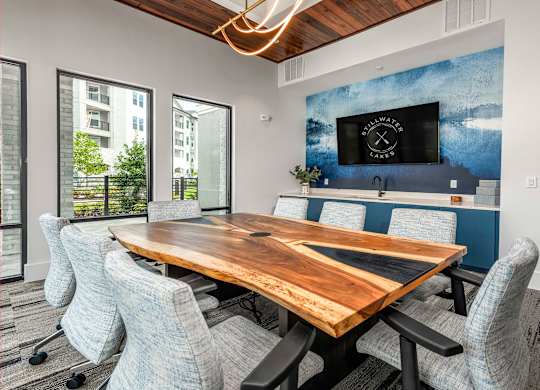 A conference room with a wooden table and grey chairs.