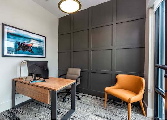 A room with a desk, chair, and a framed picture of a starry night sky.