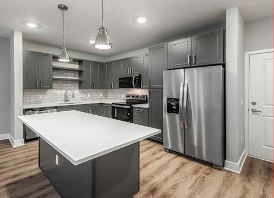 A modern kitchen with a large island and stainless steel appliances.