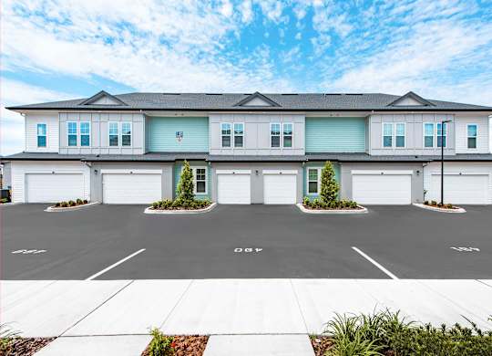 A large white house with a grey roof and a garage door.