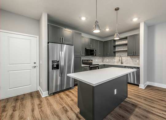 A modern kitchen with a white island and stainless steel appliances.
