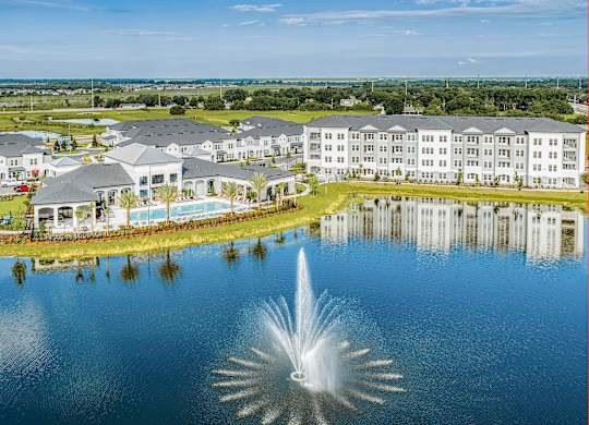 A fountain in the middle of a lake in front of a resort.