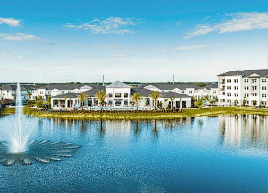 A fountain in the middle of a lake surrounded by buildings.