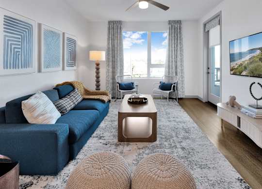 A living room with a blue couch and a television on the wall.