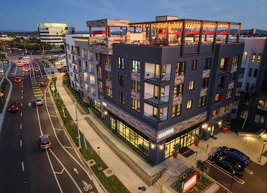 A modern building with a red sign on the ground floor.