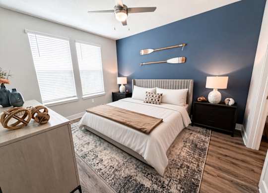 A bedroom with a bed, nightstands, and a ceiling fan.