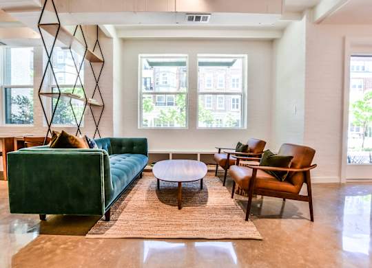 A living room with a green couch, brown armchairs, and a wooden coffee table.