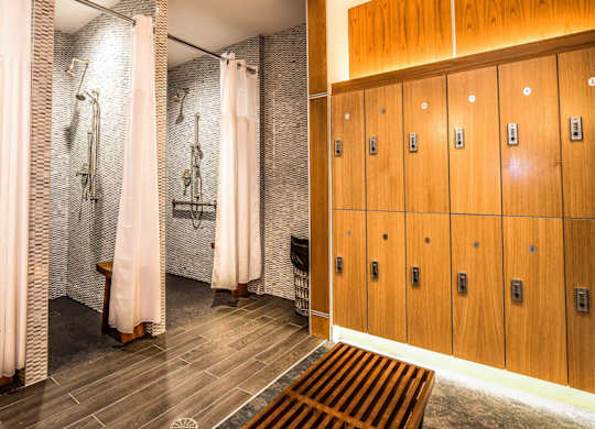 A bathroom with a row of wooden lockers and a row of white shower curtains.