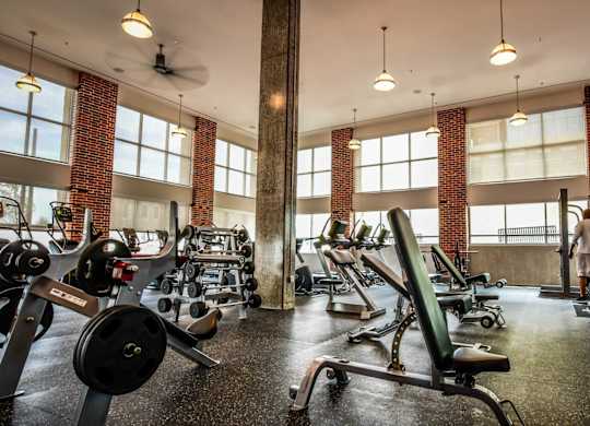 A gym with a variety of equipment and two people working out.
