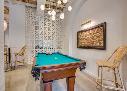 A pool table with a green cloth and a wooden frame is in the center of the room.