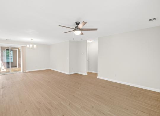 A spacious room with a ceiling fan and wooden flooring.